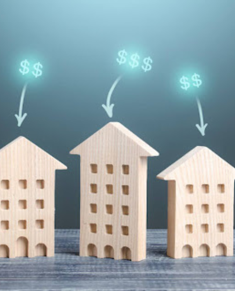 Spray Foam Insulation Contractors in Far Rockaway, NY - Five Building Models Cut Out of Wood Standing on a Grey Table with Dollar Signs in Glowing Green Above Them