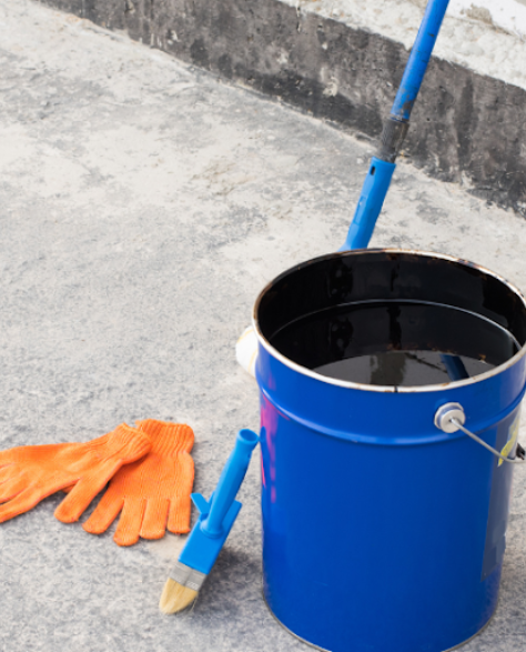 Water Damage Restoration Contractors in Copiague, NY - Waterproof Coating in a Bucket Next to Gloves and a Brush
