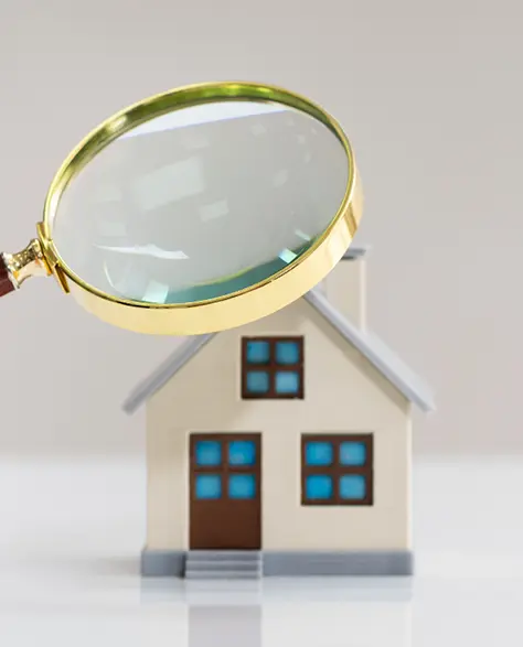 Water Damage Restoration Contractors in Hicksville, NY - A Magnifying Glass Held Over a House Model by a Man’s Hand