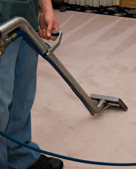 Water Damage Restoration Contractors in Long Beach, NY - A Man Vaccuming Carpet with an Commercial Vaccum