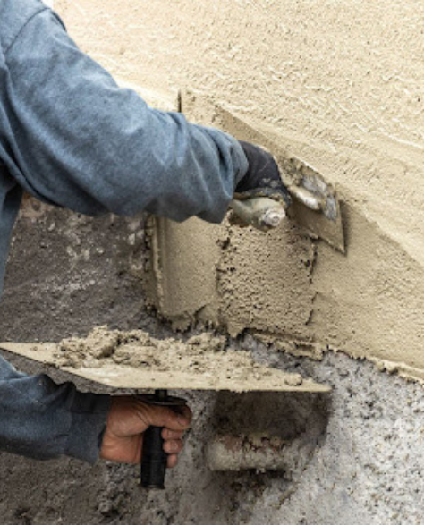 Foundation Repair Contractors in Garden City, NY - A Man Applying Cement to a Foundation Wall with a Trowel