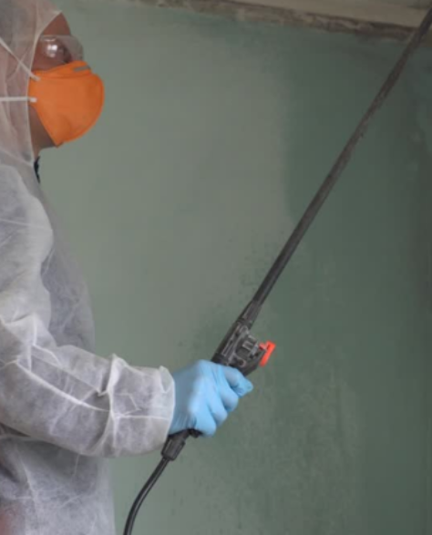 Water Damage Restoration Contractors in Park Slope, NY - A Man in a Full Protective Suit with a Spray Wand in His Hand Spraying Mold On the Wall