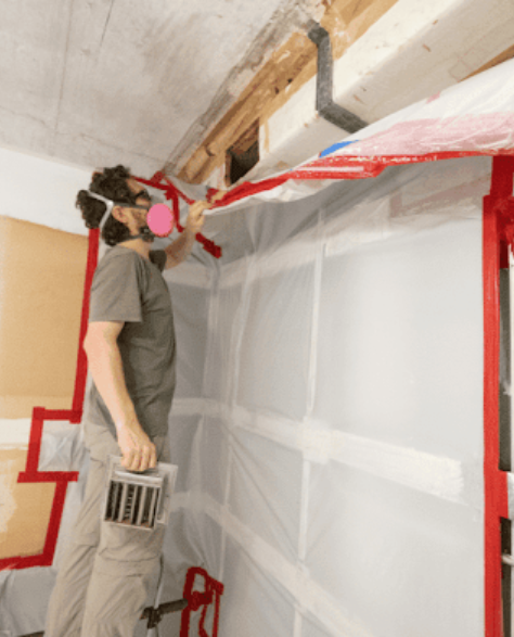Water Damage Restoration Contractors in Borough Park, NY - A man in a mask inspecting the roof for mold 