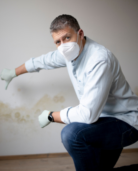 Water Damage Restoration Contractors in Homecrest, NY - A Man with a Mask Pointing to Mold Damage