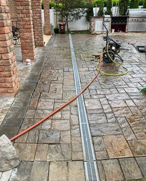 Basement Waterproofing Contractors in Richmond Hill, NY - A French Drain Installation by Zavza Seal Running Down a Back Patio