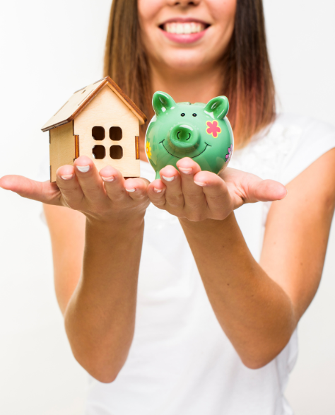 Water Damage Restoration Contractors in Rego Park, NY - A Woman Holding a House Model Next to a Piggy Bank<br />
