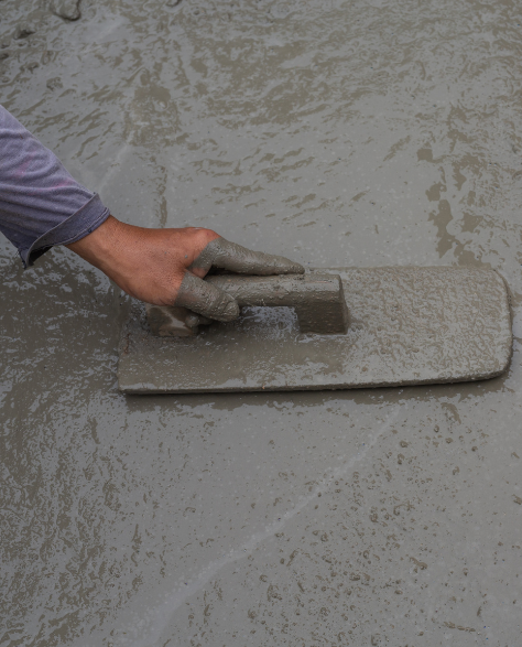 Water Damage Restoration Contractors in Sunnyside, NY - A Man Floating Cement with a Trowel to Smooth it Out<br />
