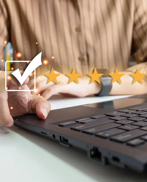 Foundation Repair Contractors in Baldwin, NY - A Man at a Table on His Laptop Pointing to a Check Box with Five Stars Behind it and Sparkles Around it