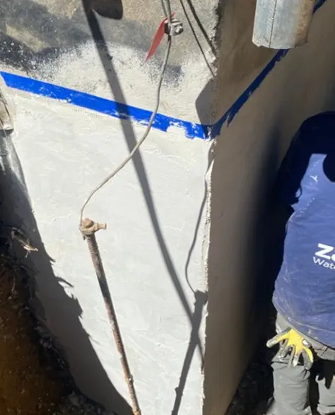 Foundation Repair Contractors in Baldwin, NY - A Foundation Repair Specialist Wearing a Company Branded Hoodie Standing by a Foundation Getting Ready to Start Work