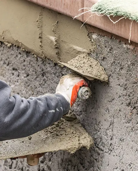 Foundation Repair Contractors in Hempstead, NY - A Foundation Repair Technician Applying Cement to a Foundation