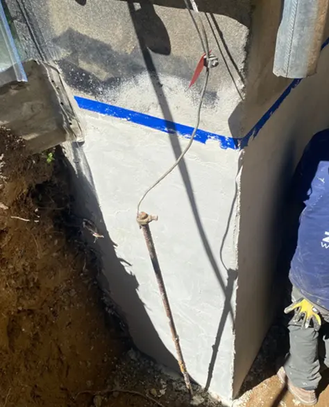 Top-Rated Foundation Repair Contractors in Hicksville, NY - Zavza Seal's Foundation Support Crew Wearing Company Logo-Branded Hoodies Working on a House Foundation