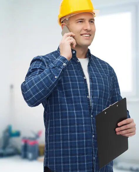 top-rated-water-damage-restoration-contractors-in-Lindenhurst-ny-1.10 Water Damage Restoration Contractors in Lindenhurst, NY - A Happy Construction Worker Wearing Yellow Is Talking on the Phone With a Clipboard in the Other Hand
