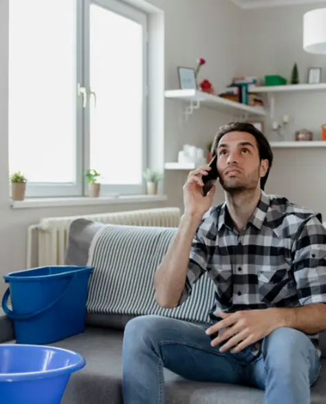 Water Damage Restoration Contractors in Deer Park, NY - A Man Holding Buckets Under Roof Leaks<br />
