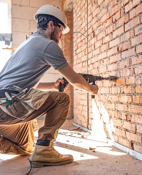 Foundation Repair Contractors in Brentwood, NY - A Man Drilling Into a Wall that the Foundation has damaged<br />
