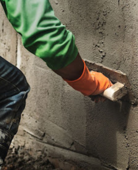 Foundation Repair Contractors in Central Islip, NY - A Man Applying Waterproof Cement to the outside of the Foundation with a Trowel<br />
