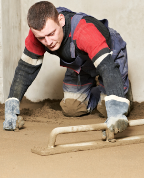 Foundation Repair Contractors in Commack, NY - A worker is keeling on the ground holding a trowel to level a foundation<br />
