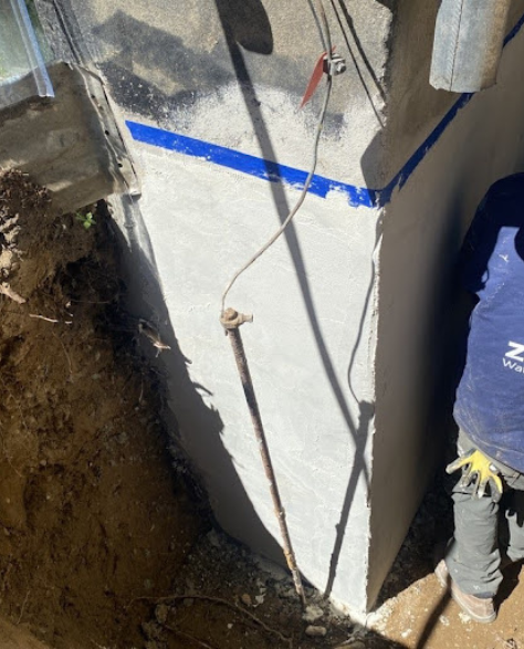 Foundation Repair Contractors in Copiague, NY - A Foundation Repair Project by Zavza Seal Showing a Worker Wearing Company Branded Hoodie Working on a Foundation<br />
