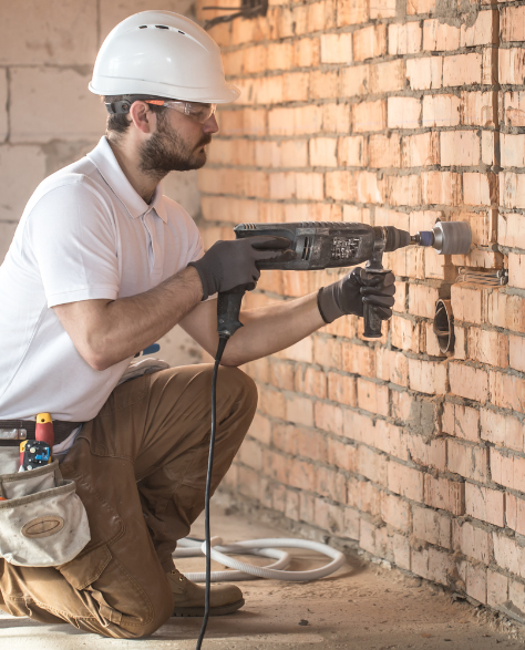 Foundation Repair Contractors in Coram, NY - A Man Drilling Into a Wall Damaged by Foundation Problems