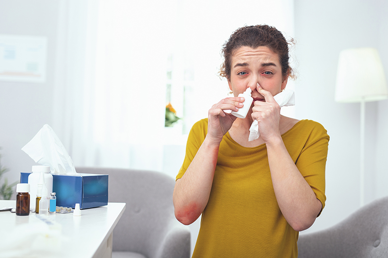 A woman using a nasal spray to clear her chemical allergies