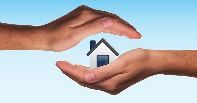 Spray Foam Insulation Contractors in Baldwin, NY - A Man's Hands Cupper Around a Small Model of a House with a Sky Blue Background