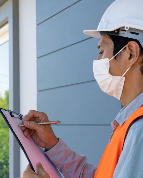 Foundation Repair Contractors in Hauppauge, NY - A Foundation Inspection Technician Writing on His Clipboard in Front of a House<br />
