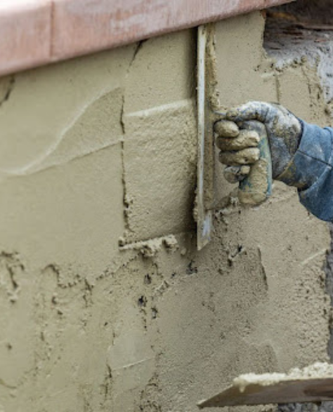 Foundation Repair Contractors in Brooklyn Heights, NY - A Man Applying Cement to the Outside of a Foundation<br />
