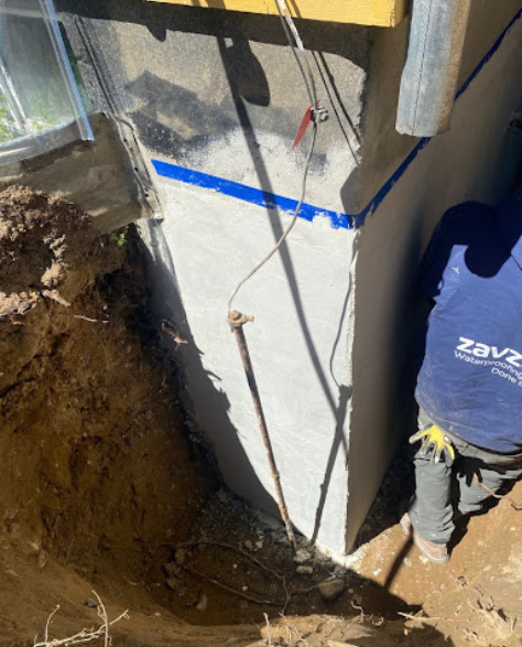 Top-Rated Foundation Repair Contractors in Huntington Station, NY - A Zavza Seal Foundation Repair Technician with a Company Branded Hoodie Working on a Foundation Support Project<br />
