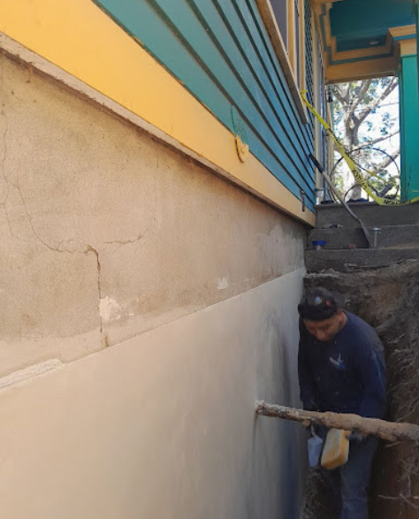 Foundation Repair Contractors in Merrick, NY - A Zavza Seal Foundation Repair Specialist in a Company Branded Hoodie Working on a Foundation<br />
