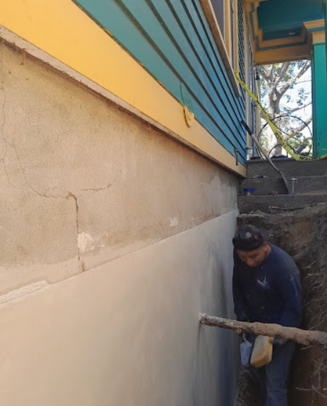 Foundation Repair Contractors in Shirley, NY - A Foundation Repair Technician Working on a Foundation Repair Project Wearing a Company Branded Hoodie<br />
