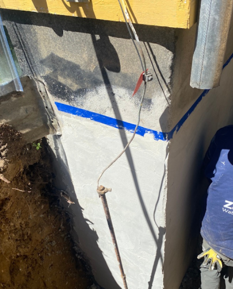 Top-Rated Foundation Repair Contractors in West Islip, NY - Zavza Seal's Foundation Repair Crew Working ON a Foundation with Company Branded Hoodies On<br />
