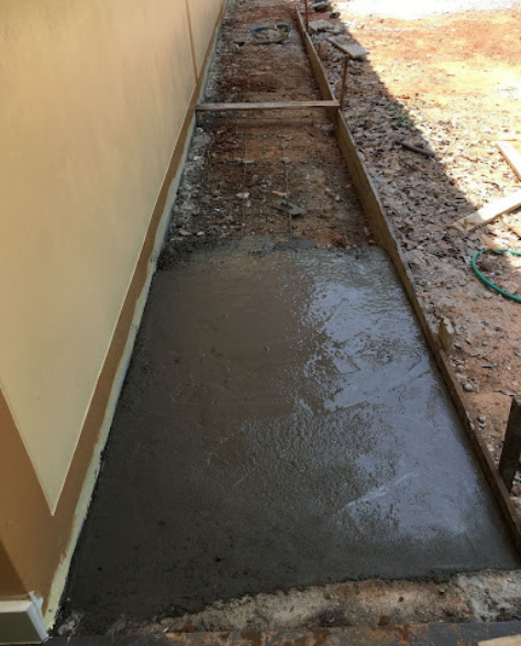 Foundation Repair Contractors in Astoria, NY - Cement Being Applied Outside of a House Near the Foundation<br />
