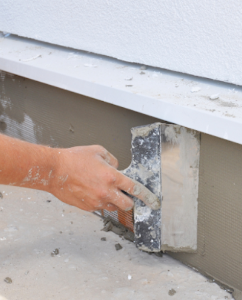 Foundation Repair Contractors in Long Island City, NY - A Man Applying Waterproofing Cement to Foundation<br />
