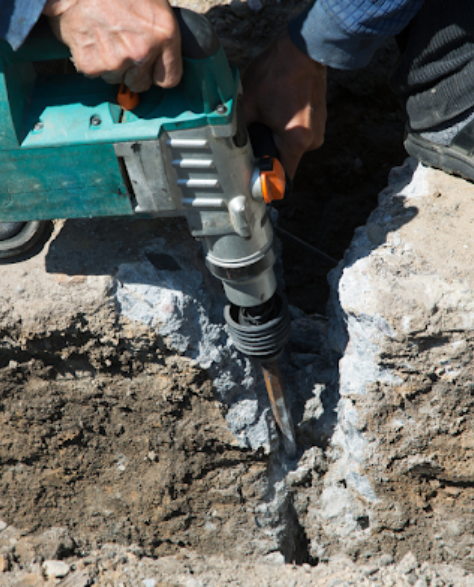 Foundation Repair Contractors in Long Island City, NY - A Man Using a Power Tool to Break Apart Cement<br />
