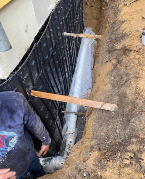 Top-Rated Foundation Repair Contractors in Jamaica, NY - A Foundation Job with Zavza Seal's Foundation Repair Experts Wearing Company Branded Hoodies Working