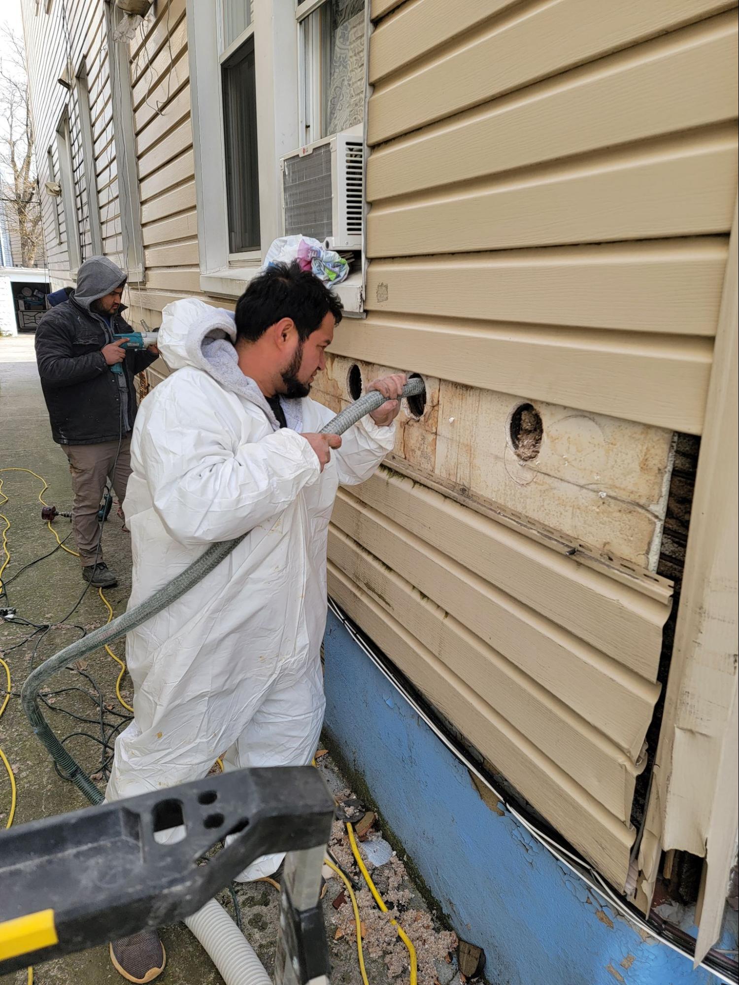 The Zavza Seal Team member blowing in R 36 insulation through the external drilled holes. 