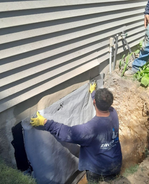 Foundation Repair Contractors in Bay Ridge, NY - A Foundation Crack Repair Project by Zavza Seal Showing a Foundation Repair Specialist in Company Branded Hoodie Working on a Foundation<br />
