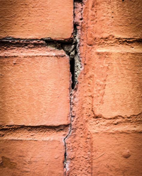 Foundation Repair Contractors in Gravesend, NY - A Brick Foundation with Foundation Cracks<br />
