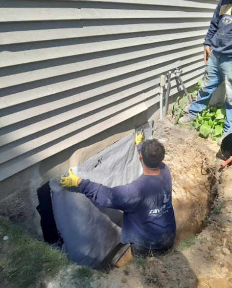 Foundation Repair Contractors in Kensington, NY - A Foundation Crack Repair Project by Zavza Seal Showing a Foundation Crack Repair Specialist Wearing a Company Branded Hoodie Working on a Foundation<br />
