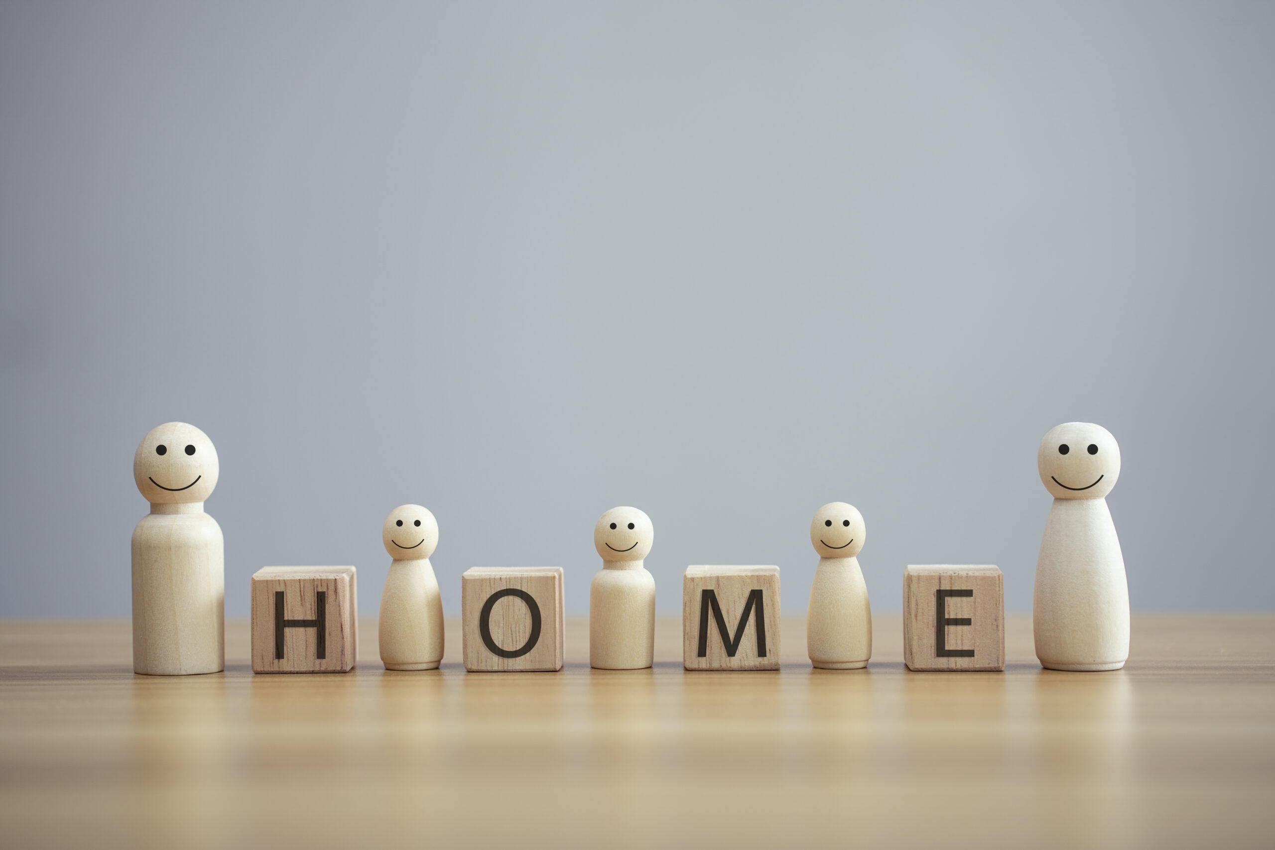 Mold Testing in New York - Little Wooden People Figures on a Wooden Table with the Word Home on Blocks Between Them