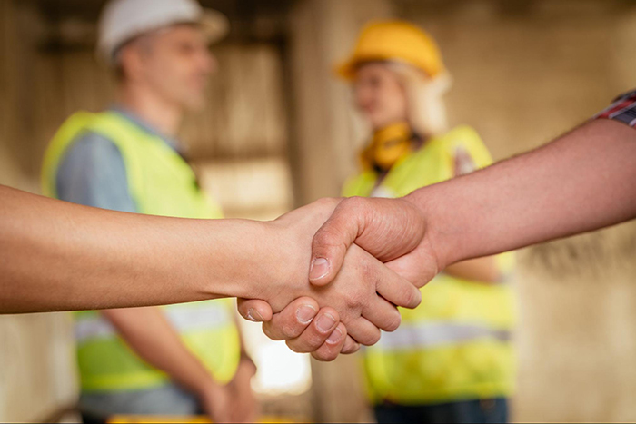 Foundation Repair, Insulation, Mold Remediation, and Waterproofing Contractors in Amagansett, NY - A Contractor and a Homeowner Shaking Hands with Two Construction Workers in the Background