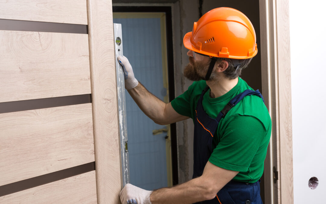 A construction worker measuring the door before installing door acoustic insulation in New York