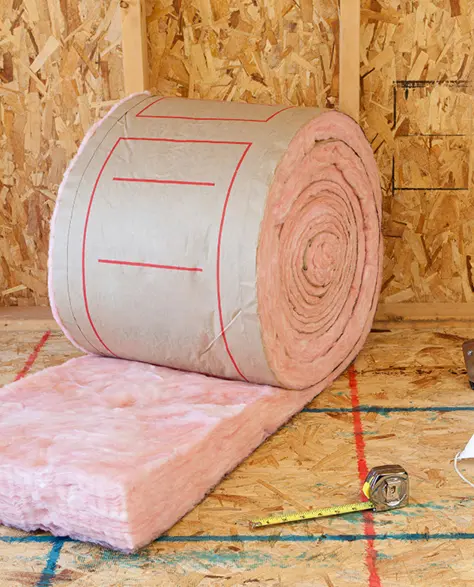 Fiberglass Insulation Contractor New York - A Roll of Pink Fiberglass Insulation Next to Some Gloves and Tools<br />
