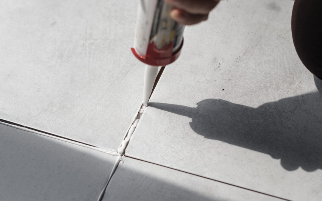 A close-up of a construction worker applying a grout sealer between tiles in a house in Long Island.