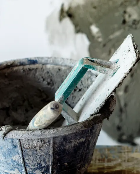 A bucket of liquid slurry along with a leveler in a steel bucket 