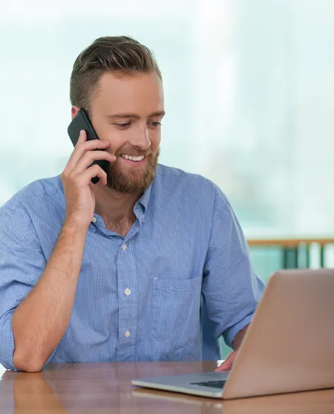 A businessman talking on the phone while using his laptop