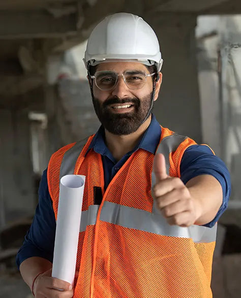 A construction worker in a hard hat and orange vest giving a thumbs up