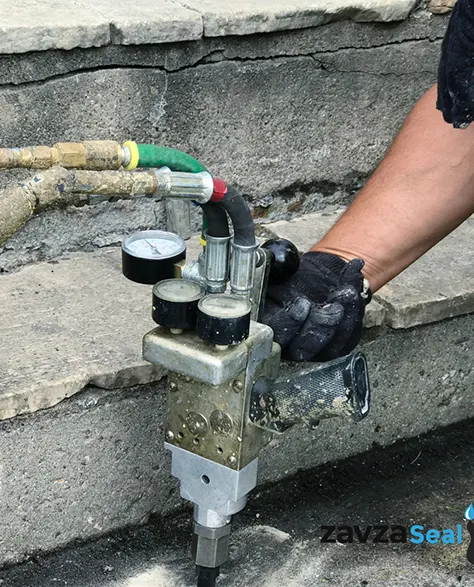 Mudjacking: A contractor using a machine to inject mudjacking slurry under the concrete to raise and level it