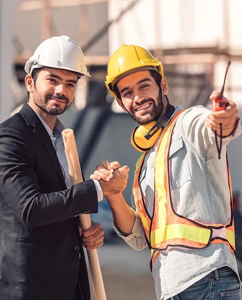 two construction workers in hard hats holding hands and smiling