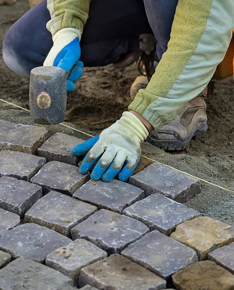 A man in gloves laying pavers on the ground