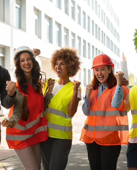 5 happy construction workers in reflective vests and hard hats raising hands and smiling in the camera